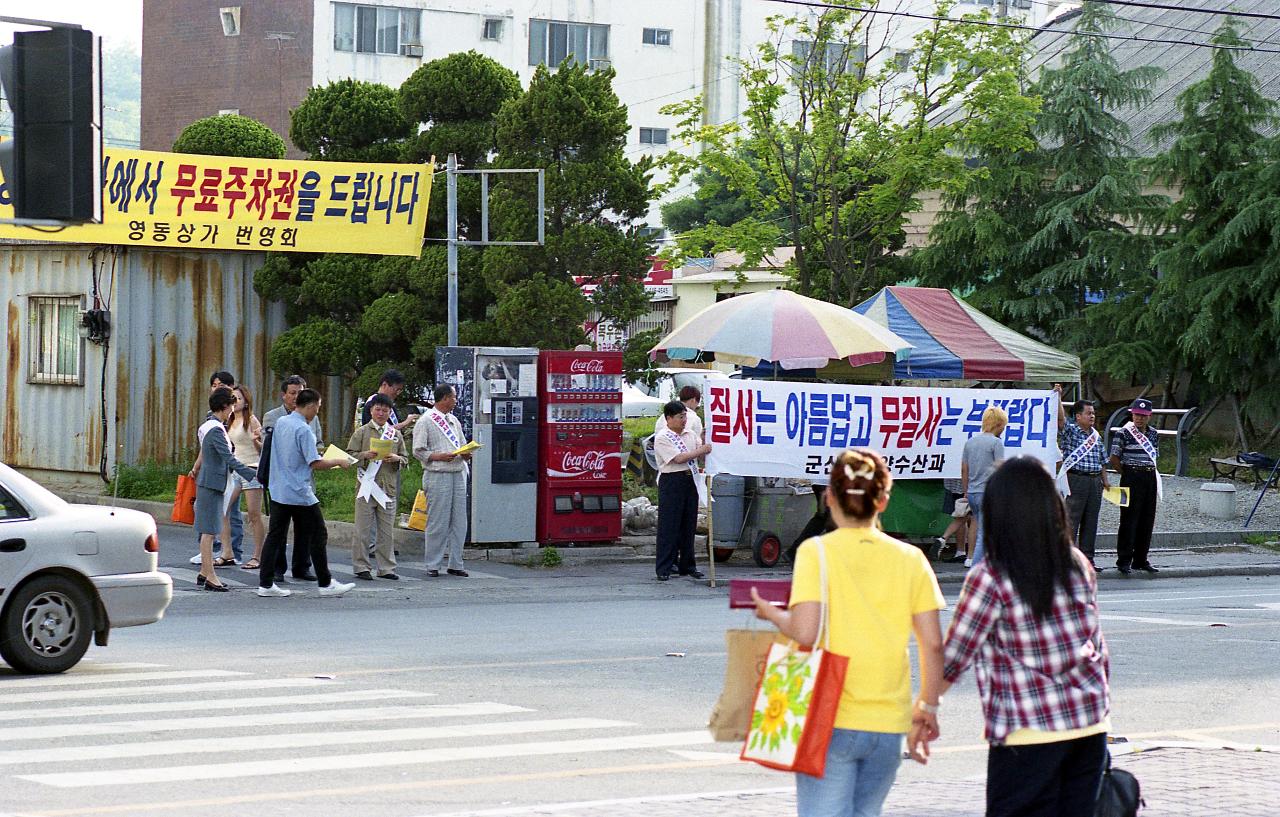 홍보물을 나눠주고있는 캠페인하는 사람들을 바라보고있는 여성들