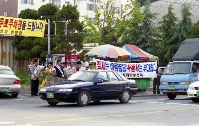 현수막을 걸고 띠를 두르며 다니는 차마다 홍보지를 나눠주는 사람들