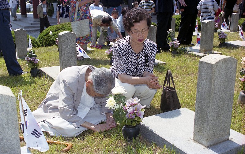묘비앞에서 기도하는 할머니와 아주머니
