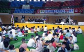 어린이 바둑대회를 맞이해 무대 위에서 말씀하고 계신 관계자와 바둑대회를 준비하고 있는 아이들사진(00001)