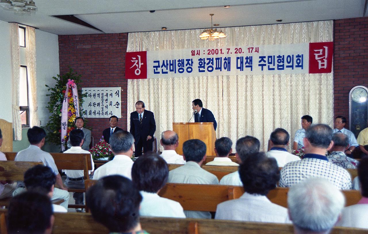 자리에서 일어나고 계신 시장님과 앞에서 시장님을 소개하고 계신 진행자와 자리에 앉아 듣고 계신 사람들