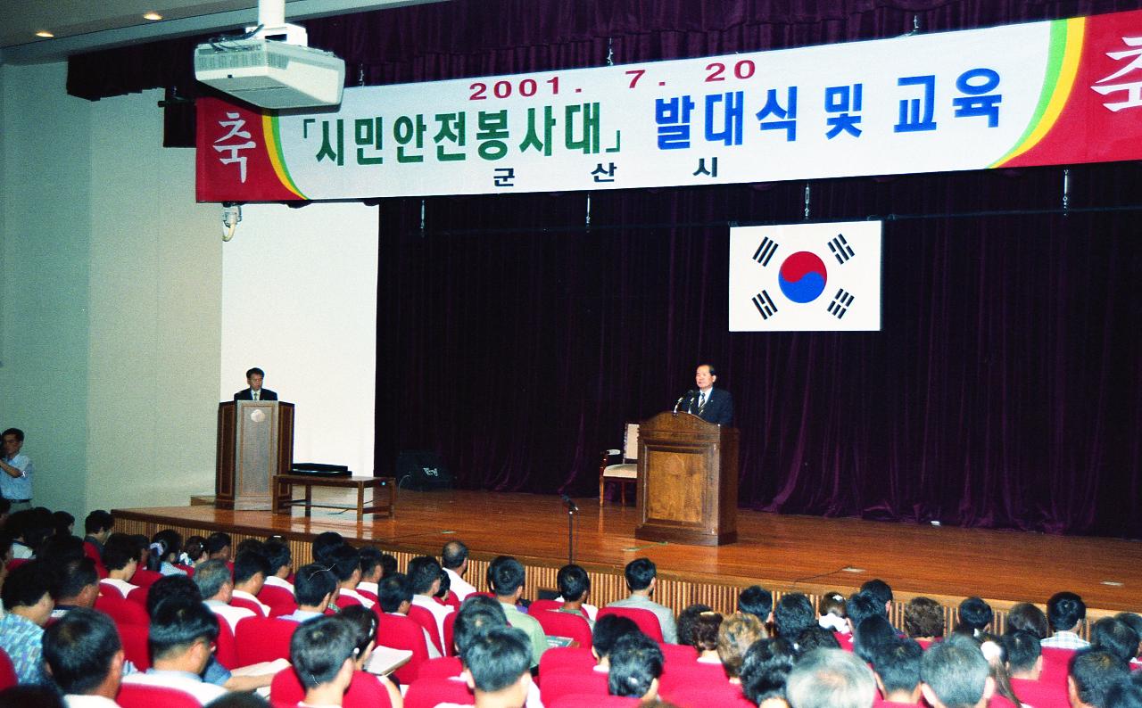 시민 안전 봉사대 발대식에서 앞으로 나와 말씀하고 계신 시장님과 자리에 앉아 듣고 계신 봉사대원들