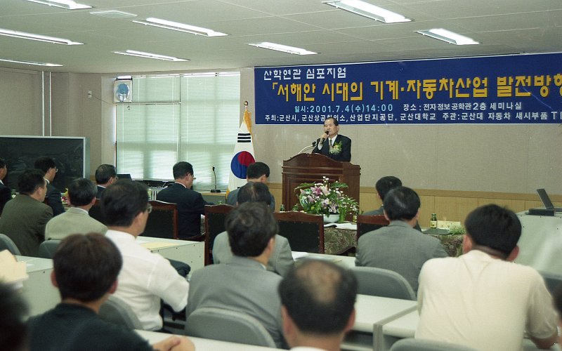 산학관련 신포지업에서 앞으로 나가 말씀하고 계신 시장님과 자리에 앉아 듣고 계신 관계자들