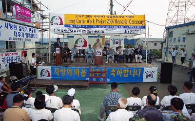 현수막이 걸려있는 무대 위에서 말씀하고 계신 시장님과 자리에 앉아 듣고 계신 사람들