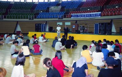 군산시 청소년 동아리 체육대회에서 앞에서 말씀하고 계신 시장님과 바닥에 앉아 듣고 계신 체육대회 참가자들