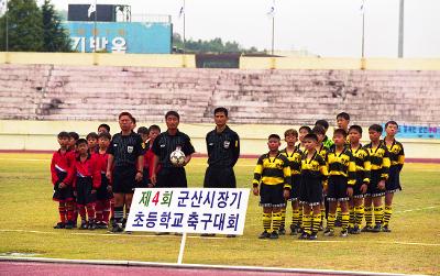 시장기 초등학교 축구대회를 알리는 팻말 뒤로 서 있는 선수들과 심판들