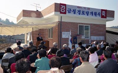 옥산 금성경노당 개원식에서 앞으로 나와 말씀하고 계신 시장님과 자리에 앉아 듣고 계신 어르신들