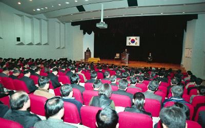 무대 위에서 말씀하고 계신 시장님과 자리에 앉아 듣고 있는 임원들