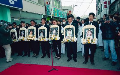 영정사진을 들고 슬픔에 잠겨 있는 사람들의 모습