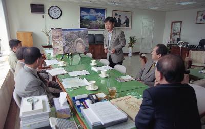 산월리 고분 중간보고회에서 자리에 앉아 자료를 가리키며 설명하고 있는 임원의 설명을 듣고 있는 시장님