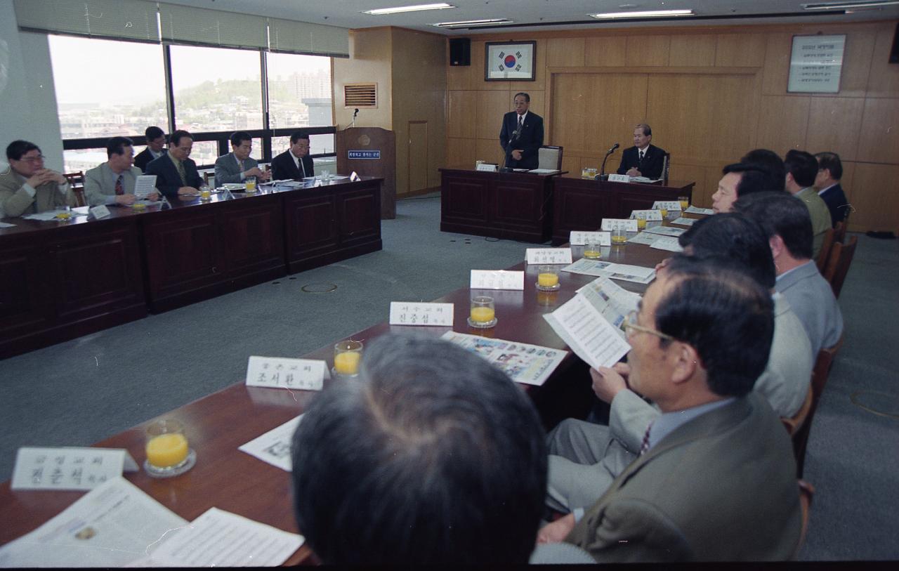 일어나 말씀하고 계신 임원과 자리에 앉아 듣고 있는 시장님과 임원들