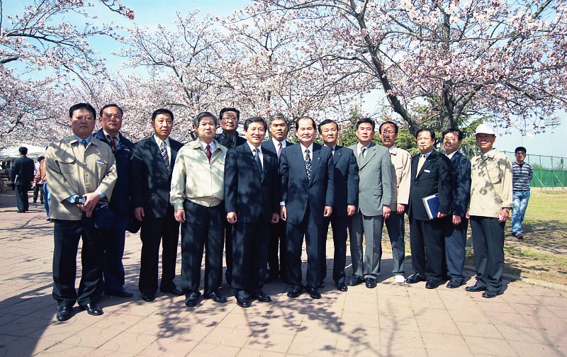 운동장을 방문한 기념으로 벚꽃나무 아래 모여서 사진을 찍고 있는 시장님과 관련인사들