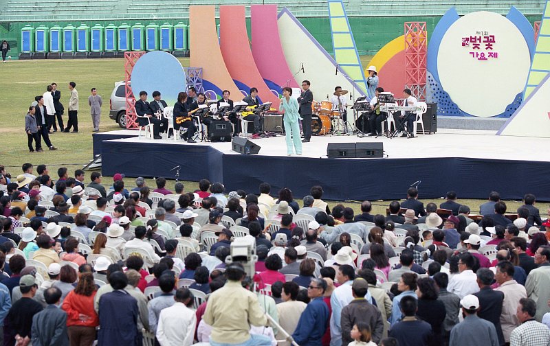 벚꽃가요제에 참가해 무대 위에서 노래를 부르고 있는 시민과 무대 아래서 구경하고 있는 시민들2