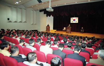 무대 위에서 말씀하고 계신 시장님과 자리에 앉아 듣고 있는 임원들