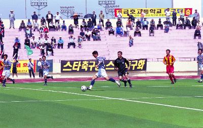 공을 몰고 달려가고 있는 선수와 뒤따라 뛰고 있는 주심