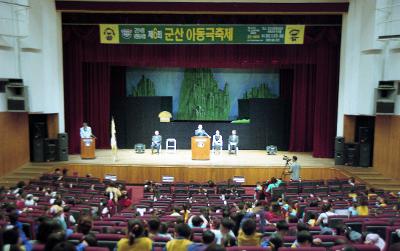 아동극 축제 무대 위에서 말씀을 하고 계신 시장님과 자리에 앉아 듣고 있는 아이들