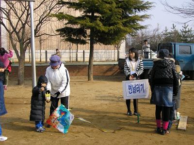 엄마의 도움을 받아서 연을 날리는 꼬마아이의 모습