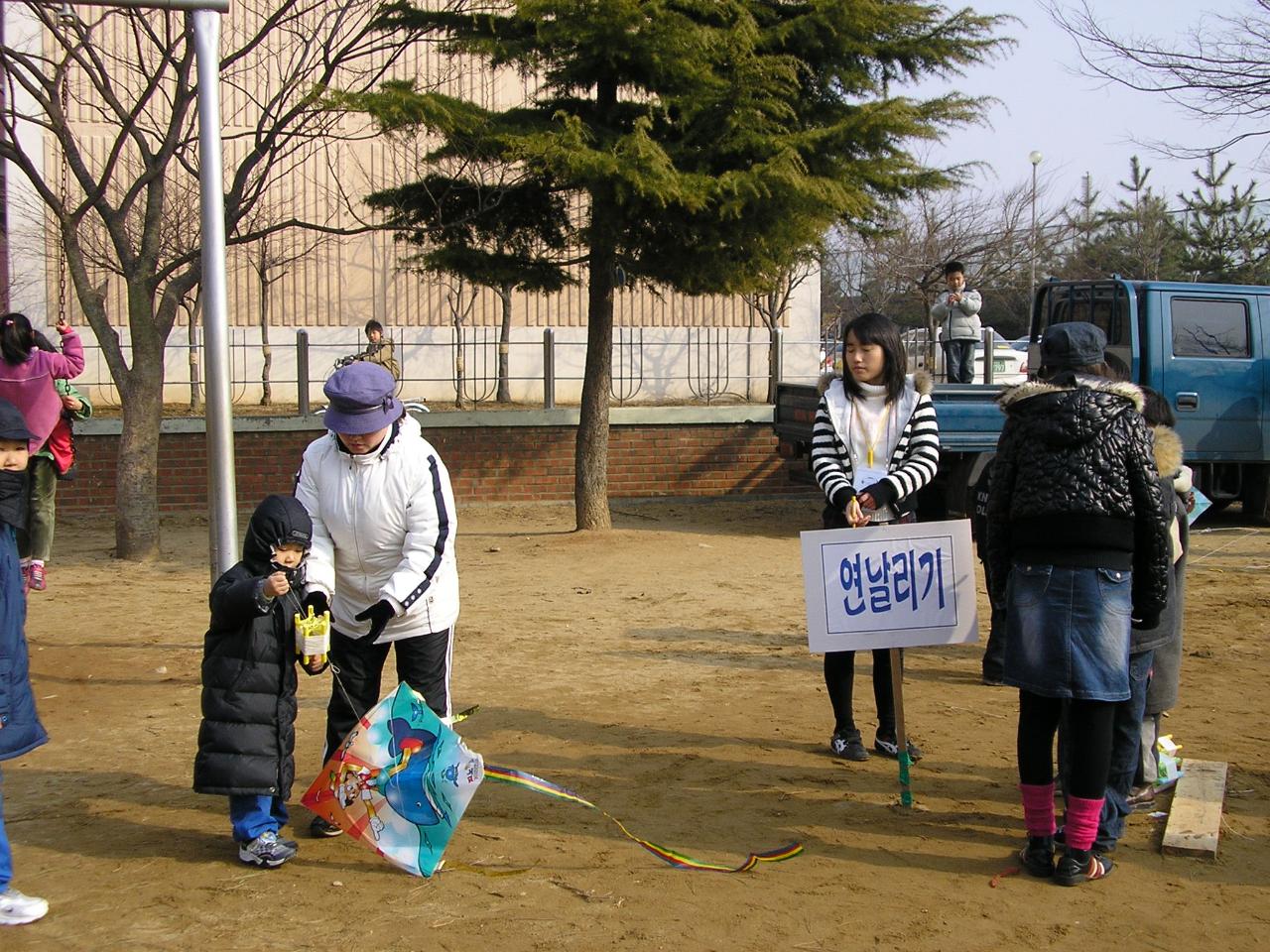 엄마의 도움을 받아서 연을 날리는 꼬마아이의 모습