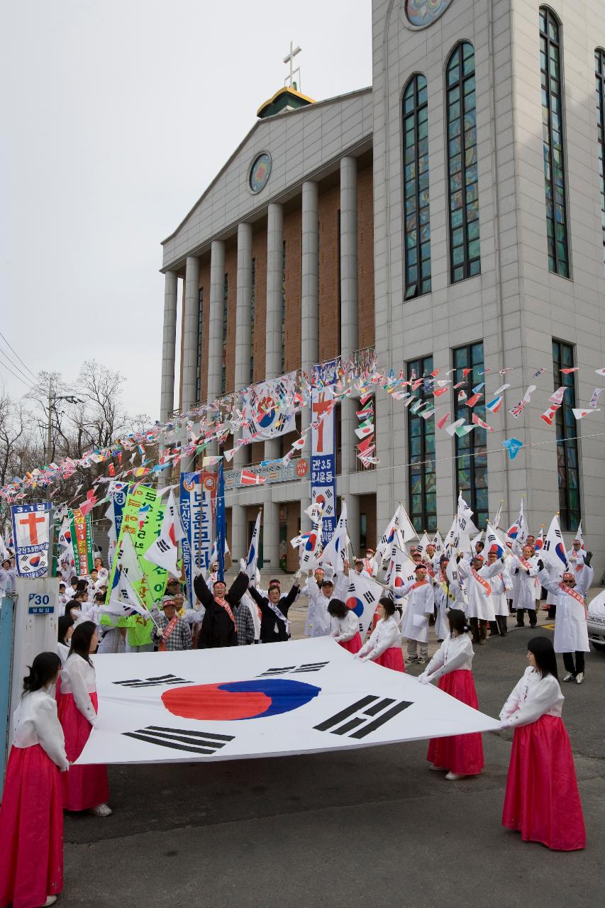 큰 태극기를 펼쳐 들고 있는 여성 참가자들과 그 뒤에서 깃발을 들고 하얀 옷을 입고있는 참가자들의 모습3