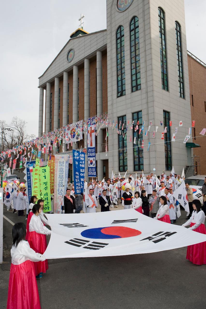 큰 태극기를 펼쳐 들고 있는 여성 참가자들과 그 뒤에서 깃발을 들고 하얀 옷을 입고있는 참가자들의 모습1