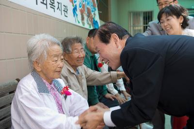 어르신께 카네이션을 달아 드리고 악수 하시는 문동신 시장님