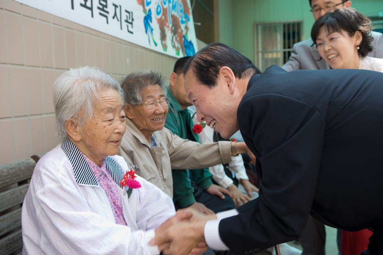 어르신께 카네이션을 달아 드리고 악수 하시는 문동신 시장님