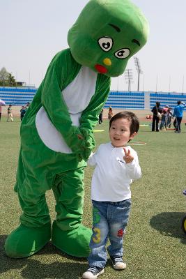 둘리 인형을 쓴 사람과 사진을 찍는 어린이