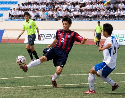 공을 차고 있는 선수와 막으려는 선수를 보고 있는 주심