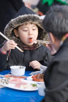 수산물 품평회에서 할아버지가 아이에게 회를 먹여주는 모습