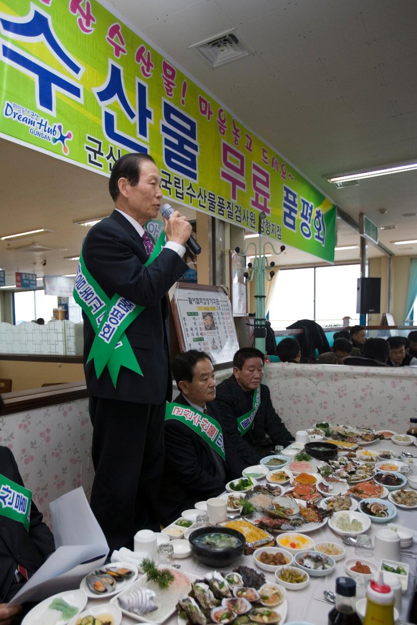 수산물이 가득 차려져 있는 상앞에 서서 말씀하고 계신 시장님과 상을 둘러 앉아 듣고 계신 임원들