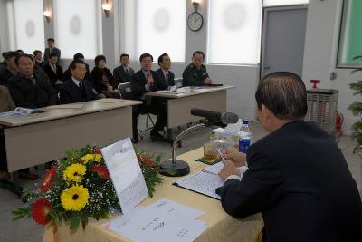 앉아서 말하고 있는 직원과 듣고 있는 시장님과 사람들