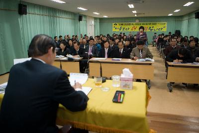 일어나 자료를 설명하고 있는 직원과 앉아서 경청하고 있는 시장님과 직원들