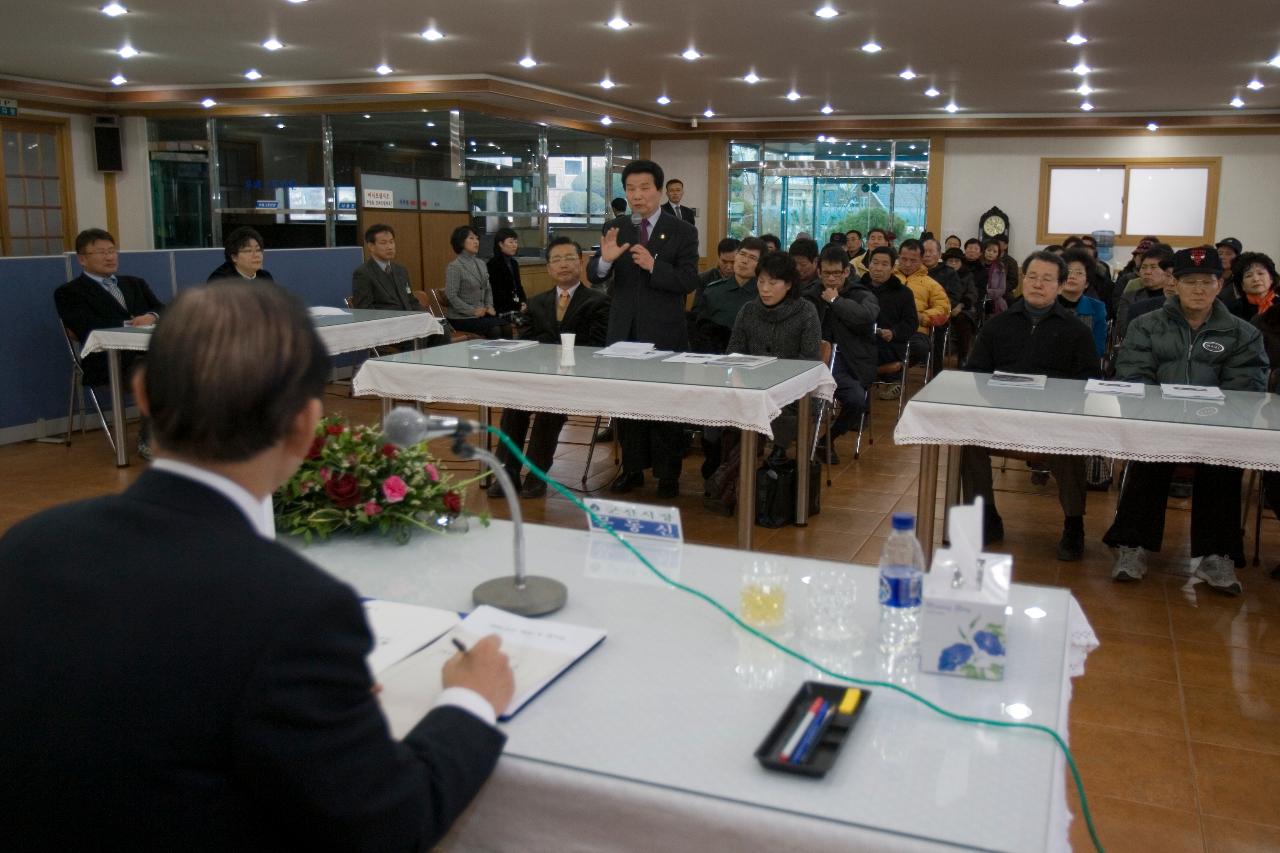 일어나 말하고 있는 직원과 자리에 앉아 경청하고 있는 사람들과 시장님