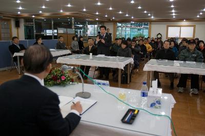 일어나 말하고 있는 직원과 자리에 앉아 경청하고 있는 사람들과 시장님