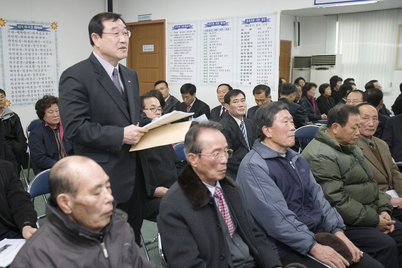 일어나 자료를 들고 말하고 계신 직원과 앉아서 듣고 계신 직원들