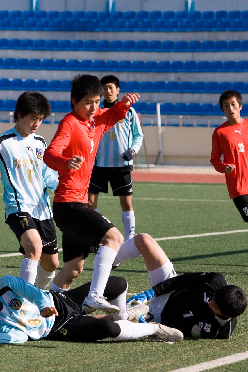 넘어져 있는 선수와 골기퍼 위를 넘어가고 있는 선수