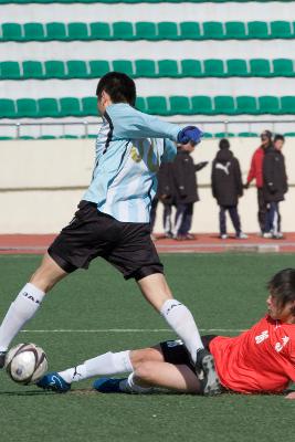 넘어지는 선수와 공을 계속 끌고 가려는 선수