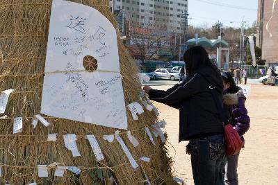 달집에 소원을 적고 종이를 붙이고 있는 사람들