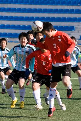 날아오는 축구공을 향해 점프하는 선수와 뛰어오는 선수들