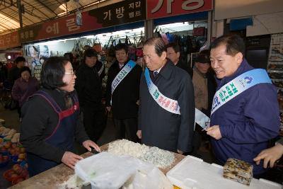 재래시장의 떡집앞에서 주민과 말씀하고 계시는 시장님과 임원들