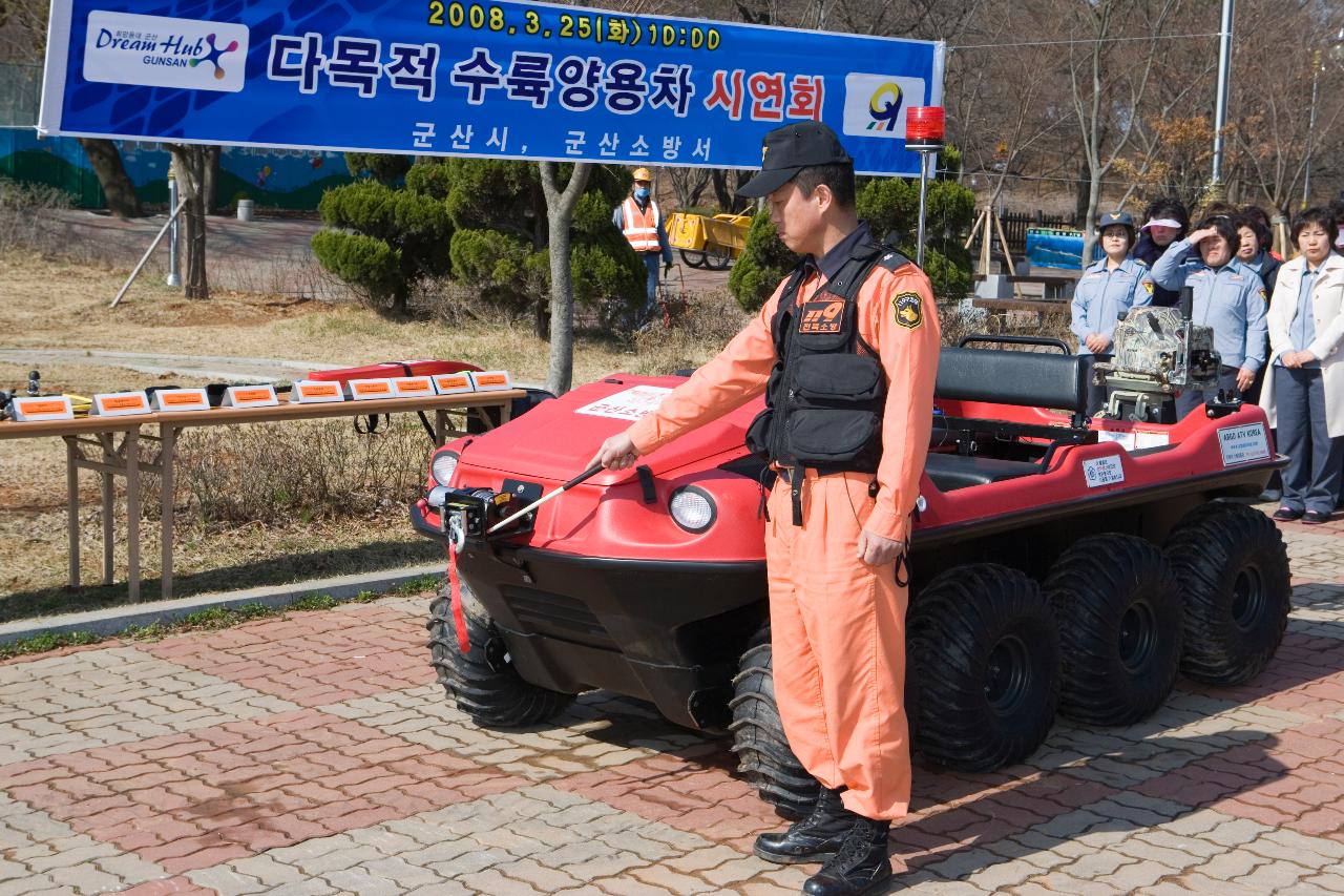 수륙양용차 시연회에서 수륙양용차 앞에 서 있는 소방관과 지켜보고 있는 사람들