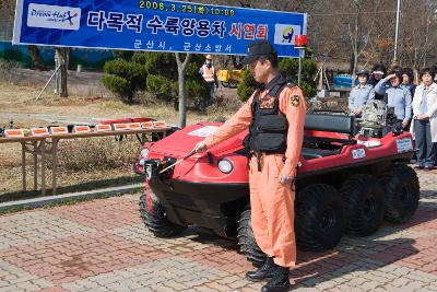 수륙양용차 시연회에서 수륙양용차 앞에 서 있는 소방관과 지켜보고 있는 사람들