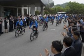 자전거를 타고 떠나고 있는 홍보단과 박수를 치며 보고 있는 임원들2사진(00005)