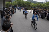 자전거를 타고 떠나고 있는 홍보단과 박수를 치며 보고 있는 임원들3사진(00006)