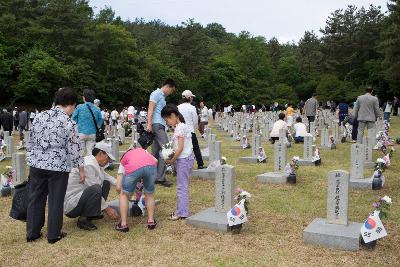 묘비에 가 꽃과 태극기를 달아주고 있는 유족들1