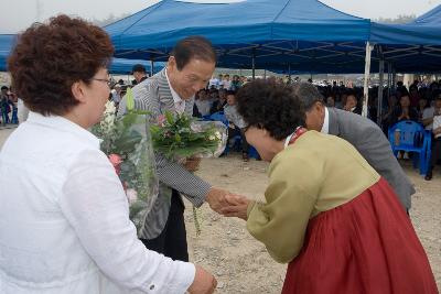 꽃다발을 전해받고 악수를 나누고 있는 시장님