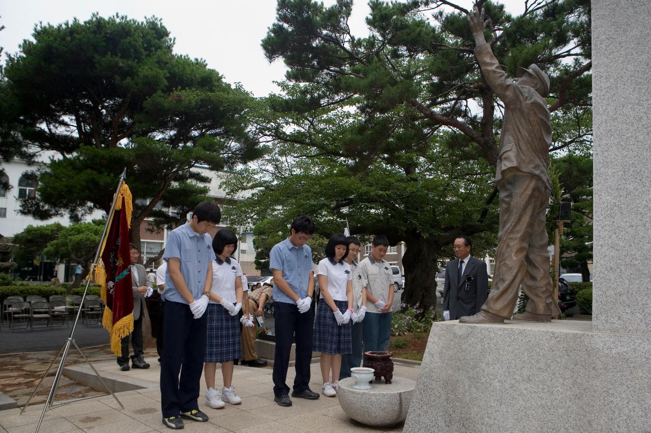 학도병의 동상앞에서 태극기를 꽂아놓고 향을 피우고 있는 학생들