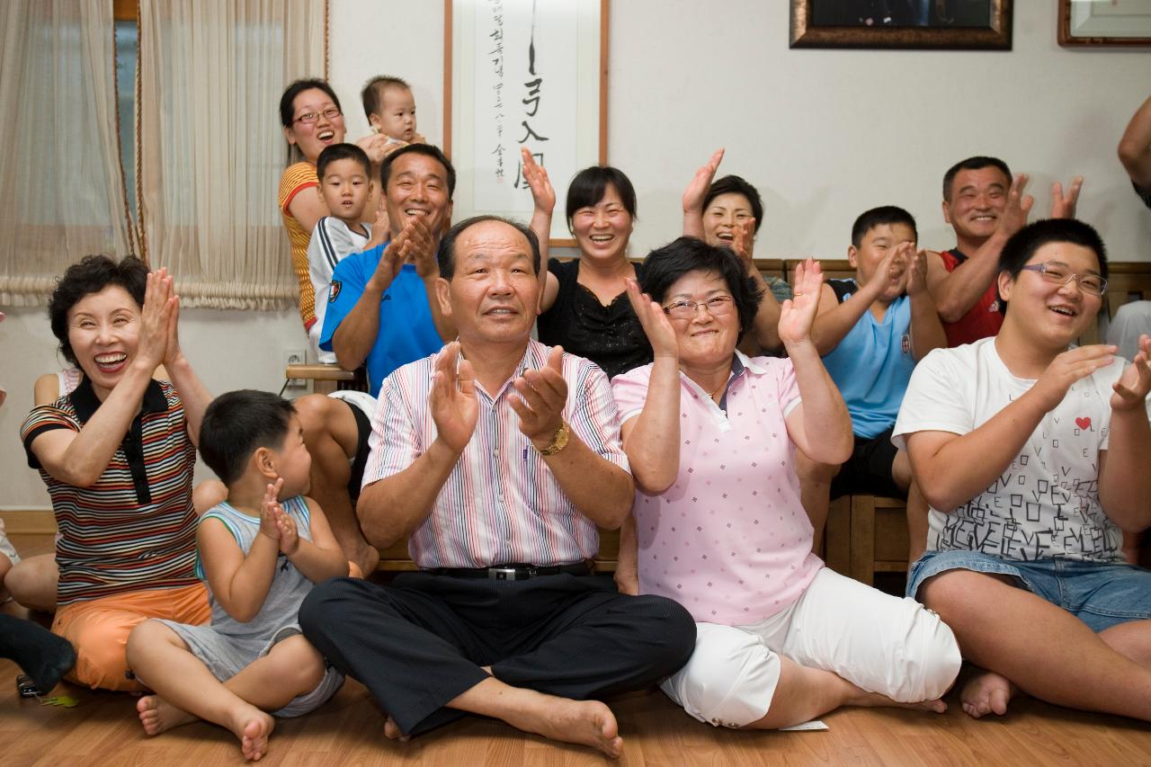 거실에 모여 앉아 박수를 치며 좋아하고 있는 박성현선수의 가족1