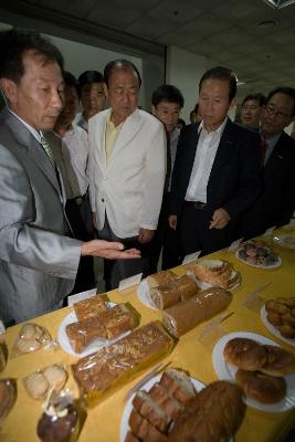 전시된 음식들을 가리키며 설명하고 있는 관계자와 듣고 있는 시장님과 관련인사들1