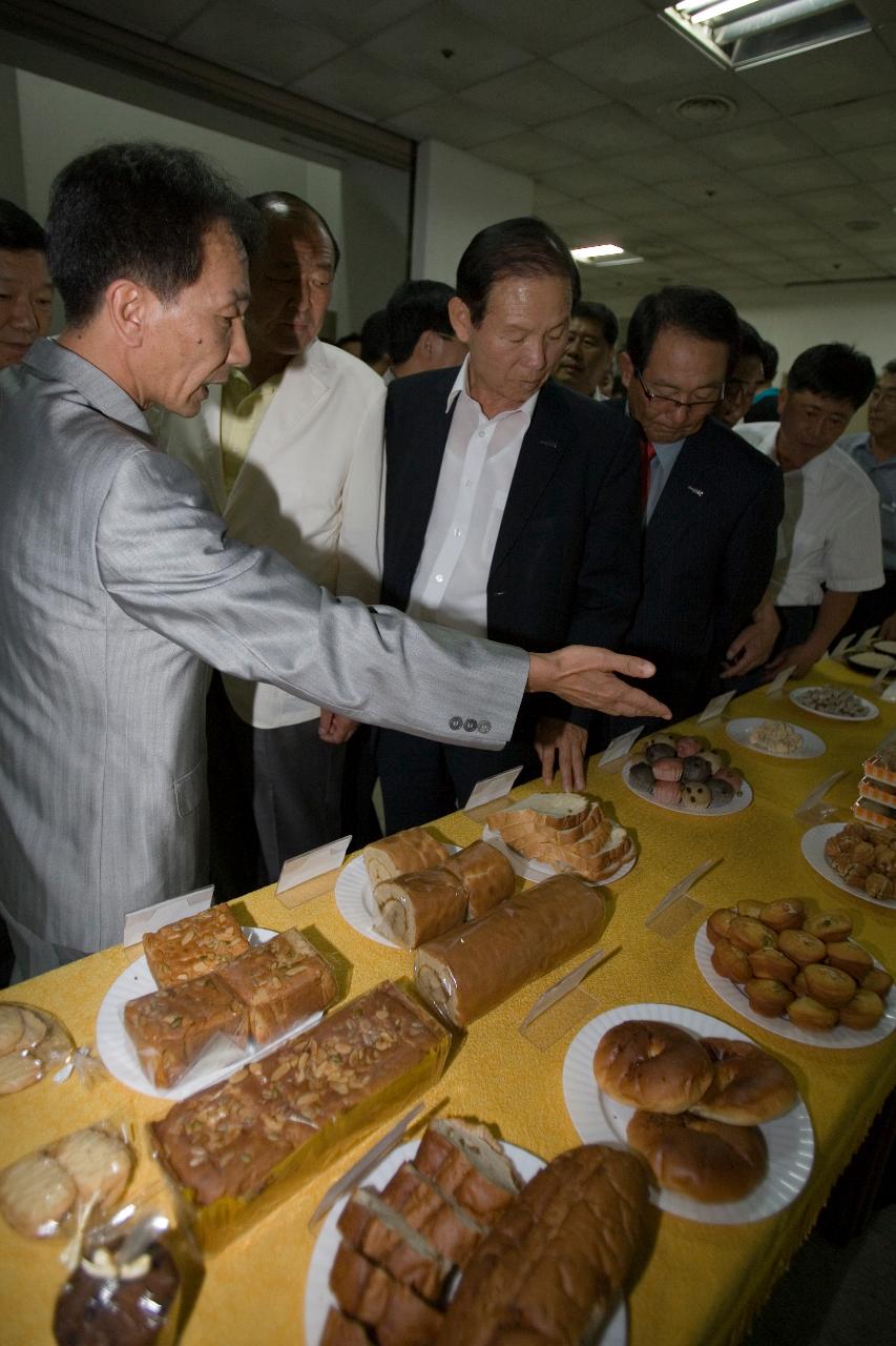 전시된 음식들을 가리키며 설명하고 있는 관계자와 듣고 있는 시장님과 관련인사들3